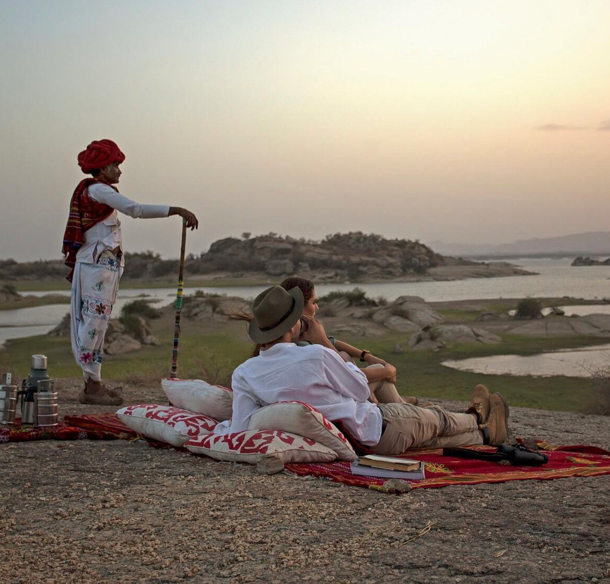 Travellers relaxing on granite rocks overlooking Jawai’s lakes with a Rabari host
